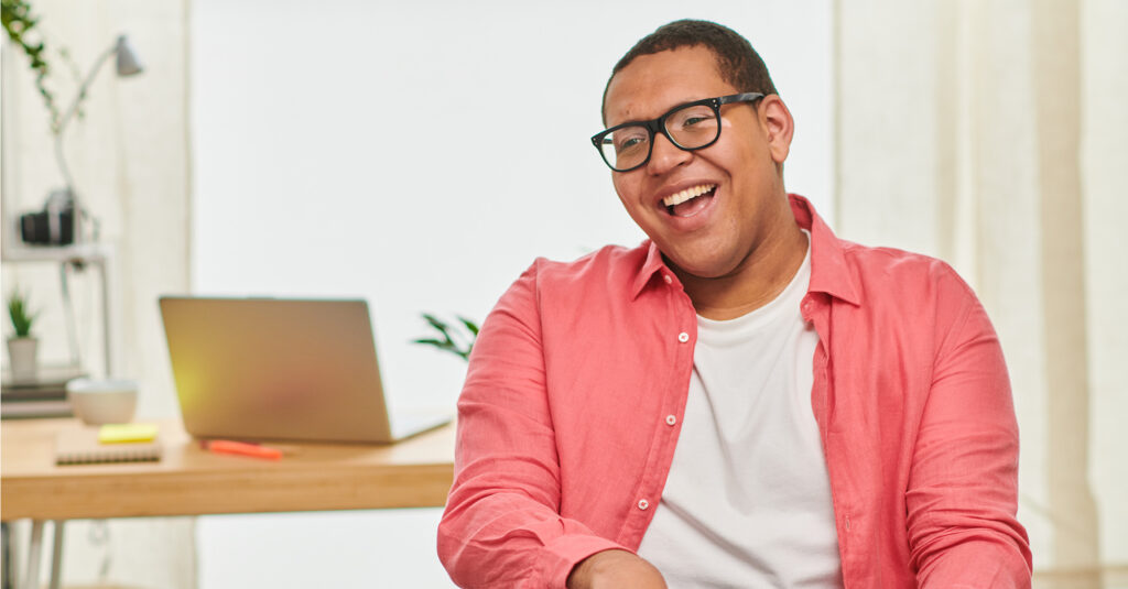 A man sits and laughs in response to a question.